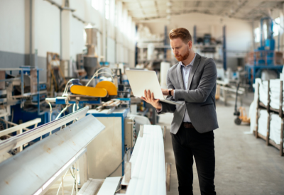 Image of a man on a laptop in a manufacturing/industrial warehouse